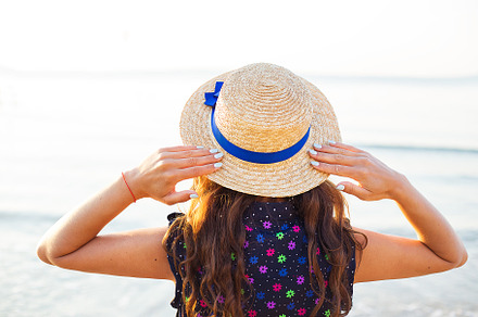 Beautiful girl in a hat stands with her back on a sandy beach, a Person Photo by Artsaba Family