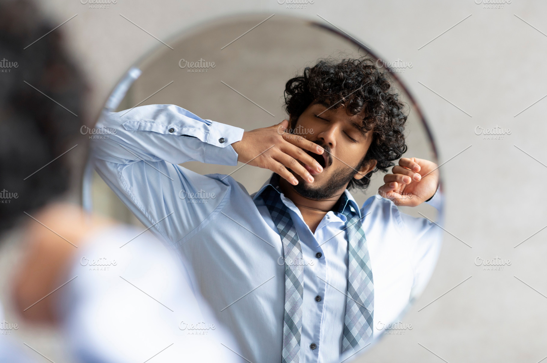 Sleepy indian businessman yawning while standing in bathroom and looking at his, a Person Photo by Prostock-Studio