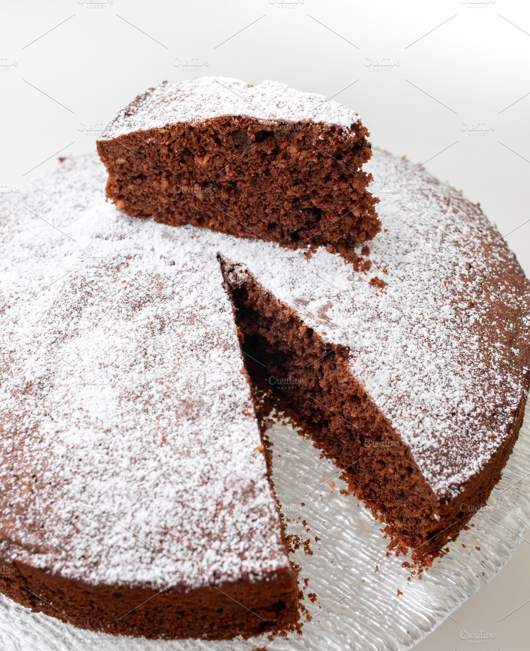 Delicious caprese cake with icing sugar resting on glass plate, a Food & Drink Photo by Antonio Gravante Market