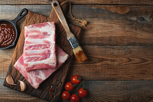 Raw pork ribs with spices, salt and rosemary on dark wooden background, a Food & Drink Photo by Budarinphoto