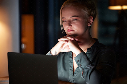 Night, laptop and thinking with woman in office for overtime, planning and strategy idea. Digital, technology and internet with employee and deadline at desk for goals, management solution and email, a Photo by Peopleimages.com