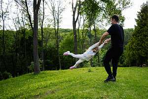 Father swinging daughter playfully in a green forested outdoor setting, a Person Photo by AS photostudio