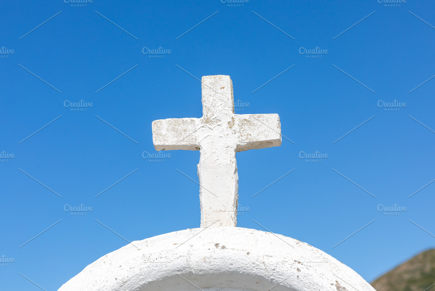 White cross standing on whitewashed dome against blue sky, a Photo by Antonio Gravante Market
