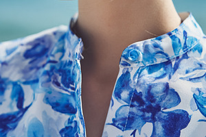 Woman wearing blue floral blouse and shell earring, wind blowing, a Photo by Studio ANNA