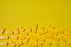 Scattered yellow plastic toy building bricks on a solid yellow b, a School & Education Photo by ndanko