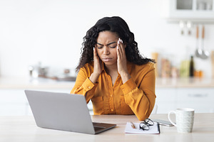 Black lady freelancer suffering from headache while working