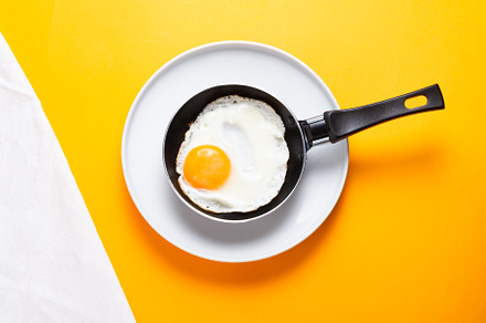 Scrambled, frying  eggs from one egg in a small pan on yellow ba, a Food & Drink Photo by MDBildes