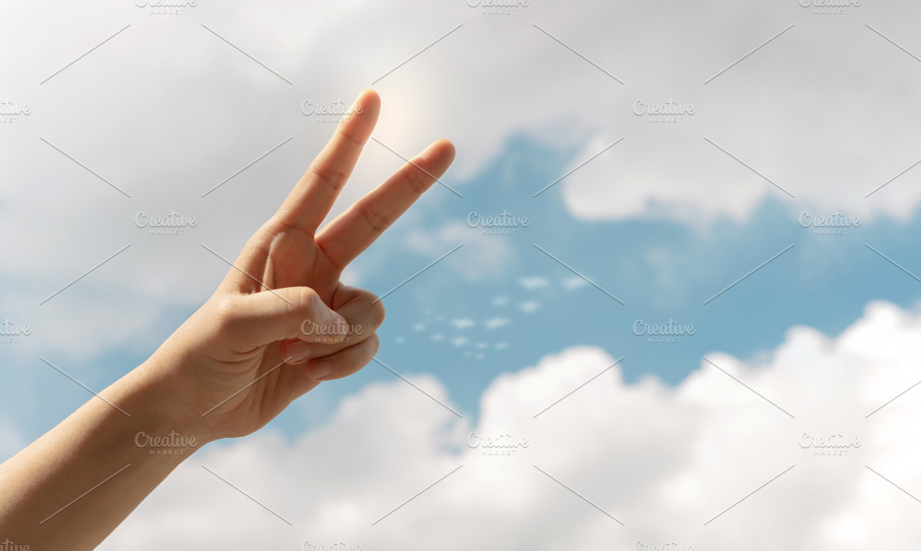 Hand making a peace sign against a bright blue sky, symbolizing, a Photo by salmon.black