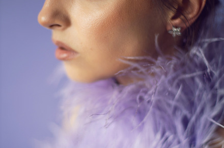 portrait woman in an evening purple dress with feathers stands in the backgroun, a Person Photo by SaulichPhoto