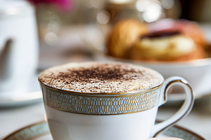 Cappuccino with cocoa powder and a macaron cookie on an elegant, a Food & Drink Photo by Studio ANNA