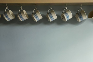 Row of hanging vintage cups with blue floral pattern on kitchen shelf. Cotswold, a Photo by Studio ANNA