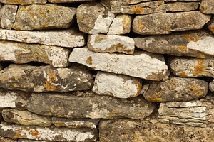 Dry stone wall texture showing stacked rocks with lichen and mos, a Photo by Studio ANNA