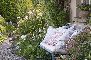 Tranquil spring garden path with a blue metal bench and decorati, a Photo by Studio ANNA