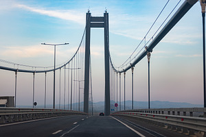 Wide angle view of an empty suspension bridge at dawn, featuring clear blue sky, an Architecture Photo by Ales Munt