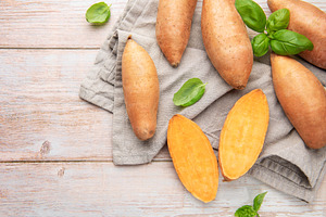 Raw sweet potatoes on wooden background preparing healthy meal, a Food & Drink Photo by Olena Rudo