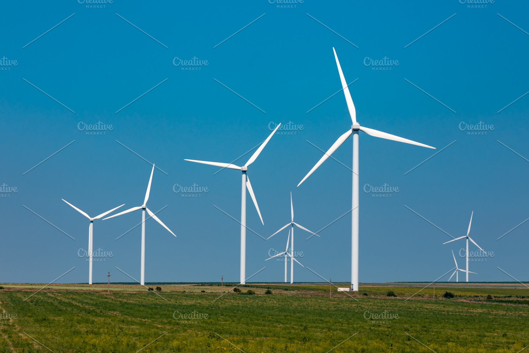 Wind turbines generating renewable energy on a grassy plain under a clear blue, a Technology Photo by Ales Munt