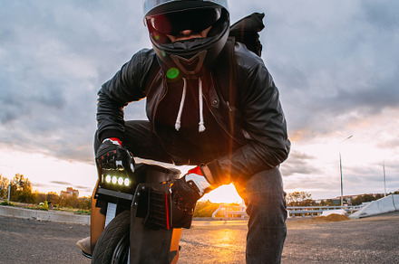 rider in a helmet with sunglasses rides on an electric mono whee