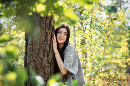 Young woman enjoying a peaceful moment by a tree in a lush green, a Person Photo by Olena Rudo