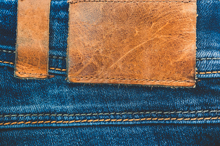 Denim background blue jeans with a brown leather label empty space stock, a Beauty & Fashion Photo by Marmoset's Market