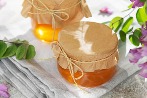 Honey jars with acacia flowers on white surface, a Food & Drink Photo by Olena Rudo