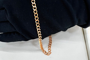 Elegant golden chain displayed on black fabric in a professional setting, a Photo by AS photostudio
