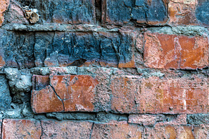 Close-up of an old red brick wall with chipped edges, dark stain, a Background Photo by Ales Munt
