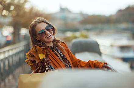 happy trendy woman in orange trench coat with shopping bags, a Person Photo by Alliance Images