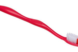 Plastic red toothbrush on isolated background, close up, a Health & Medical Photo by ndanko