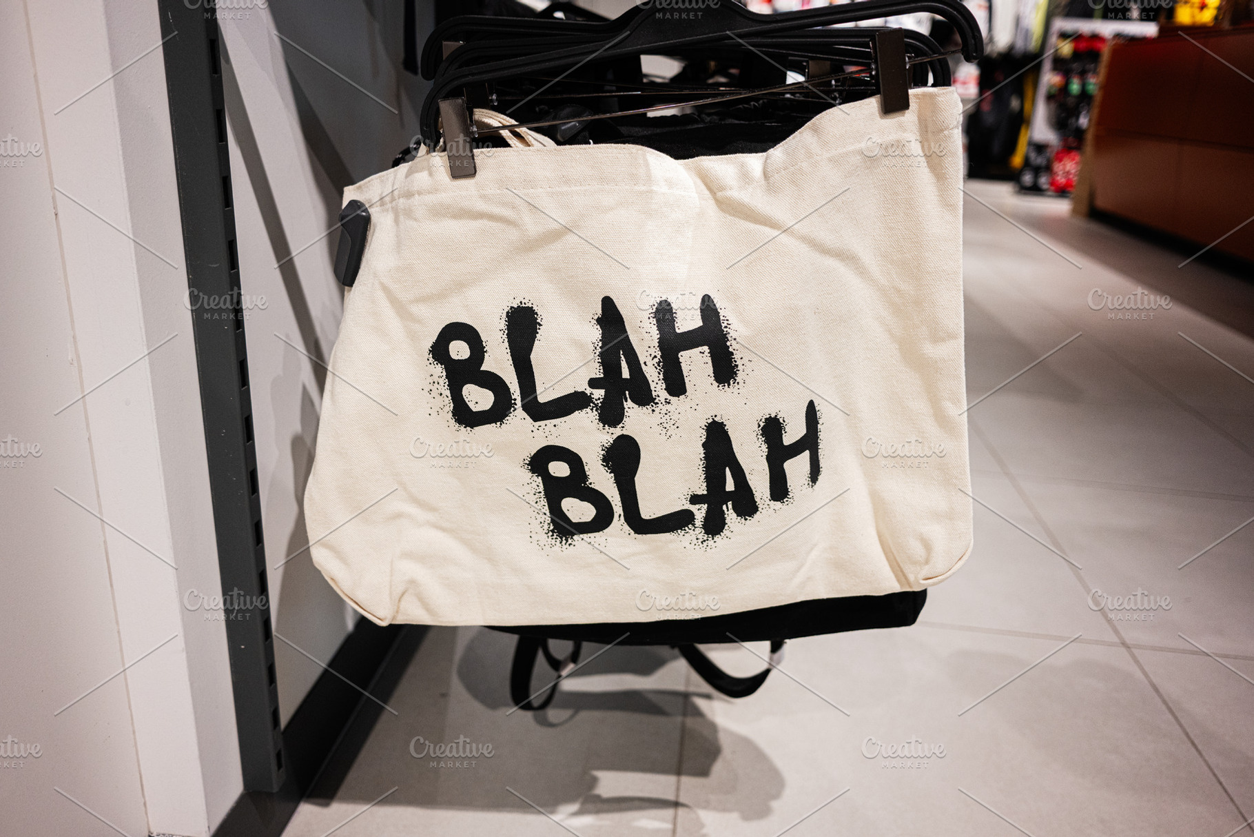 Canvas tote bag with Blah Blah lettering text displayed in a retail store rack, a Photo by AS photostudio