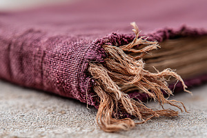 Detailed view of an aged book cover with frayed edges resting on a surface, a Photo by AlyaAnd