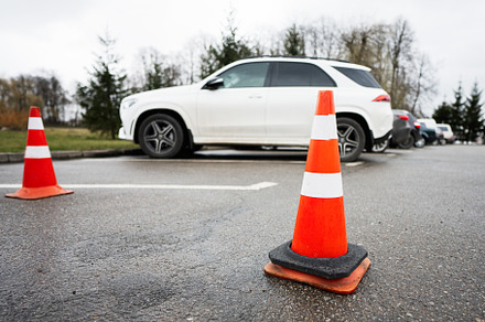 Traffic orange cones standing on a street along the parking cars, a Photo by AS photostudio