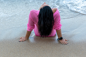 Back view of woman in pink sweater sitting on shore with waves, enjoying the pe, a Person Photo by Ales Munt