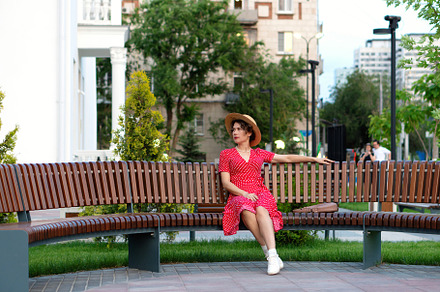Woman in red dress and hat poses