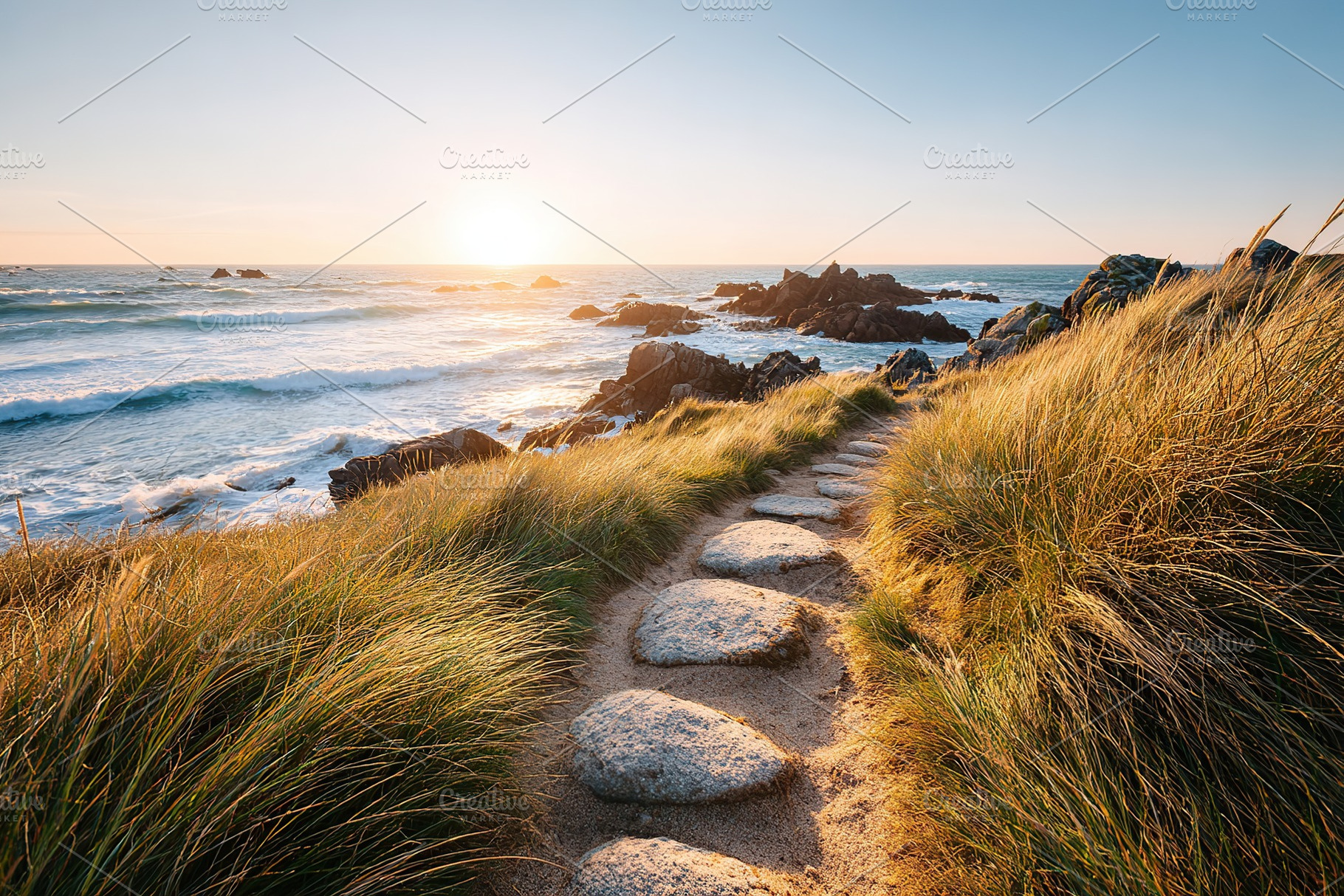 Walk along a quiet coastal path at sunset with golden light on the ocean, a Photo by AlyaAnd