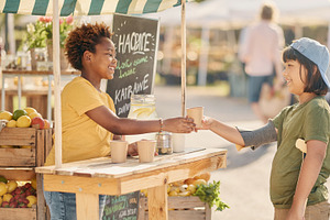 Children interacting at a outdoor wooden lemonade stand market, a Person Photo by DanFLCreativo