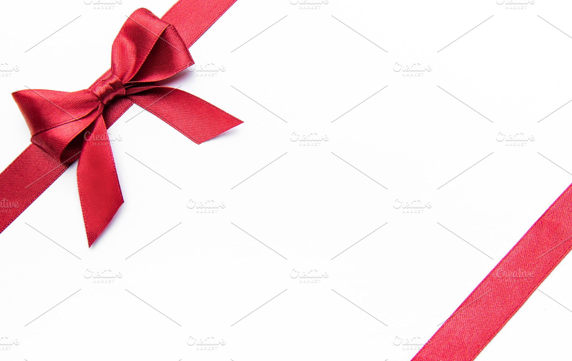 Red ribbon bow on a white background creating border, a Holiday Photo by Olena Rudo