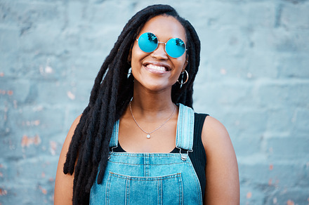 Portrait of black woman with sunglasses in the city and a smile on her face. Young fashion model, summer and happy girl with glasses, trendy accessories and street clothes smiling in an urban town, a Photo by Peopleimages.com