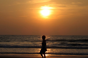 Woman silhouette at sunset beach, a Photo by saiko3p