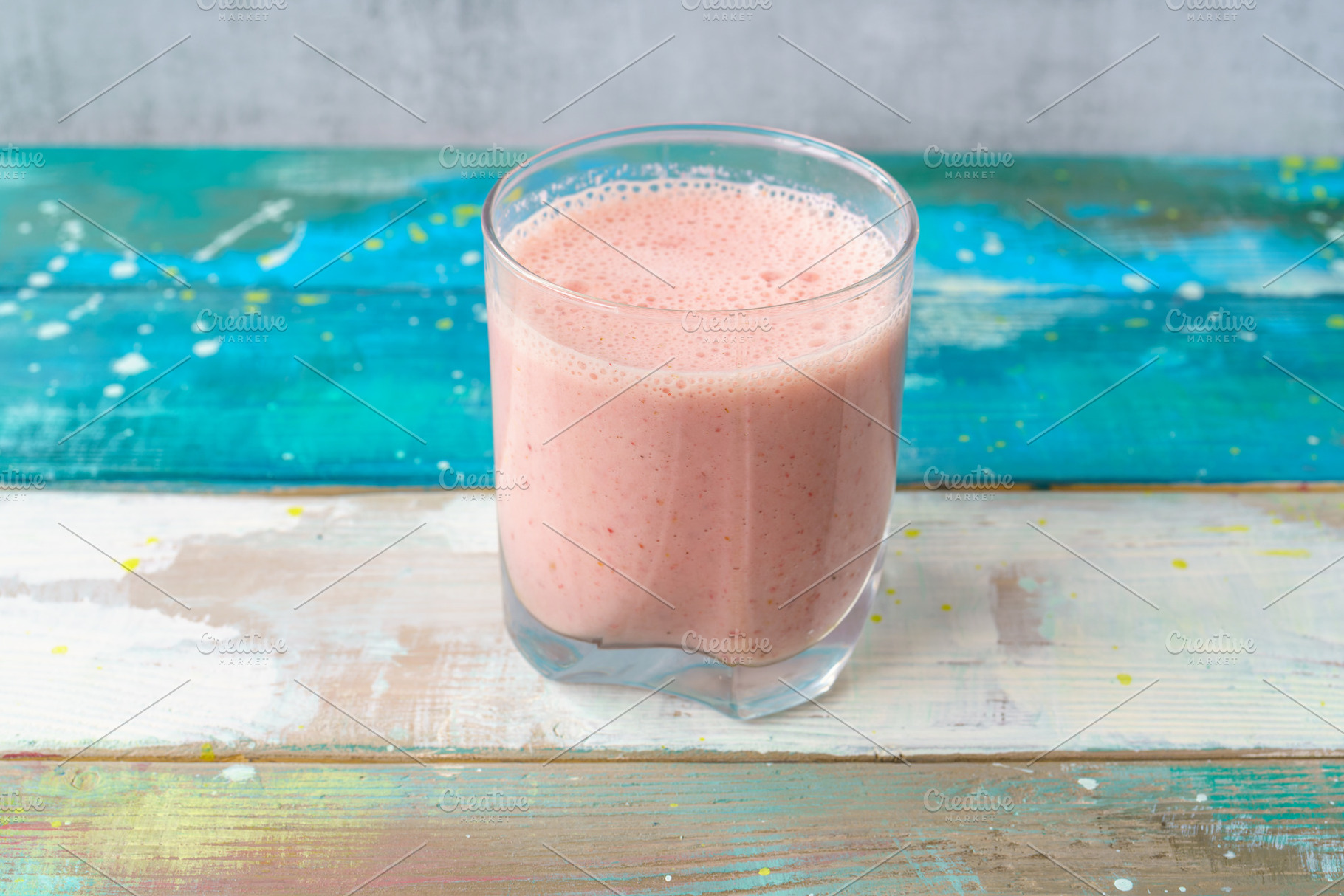 Fresh pink smoothie in clear glass on colorful wood background. Healthy refresh, a Food & Drink Photo by Eugene_Photo