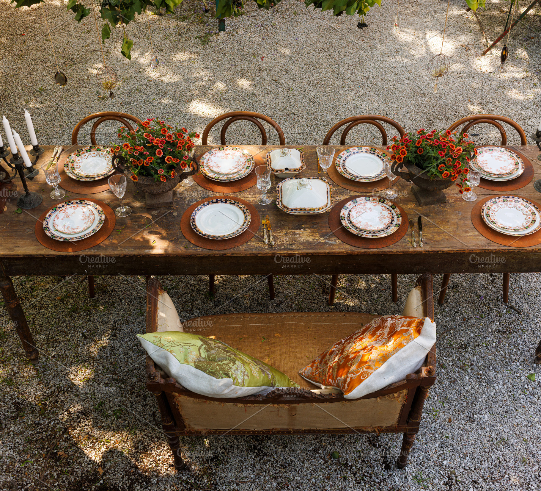 Wooden outdoor table in a garden courtyard set with vintage plat, a Food & Drink Photo by Bepslabor
