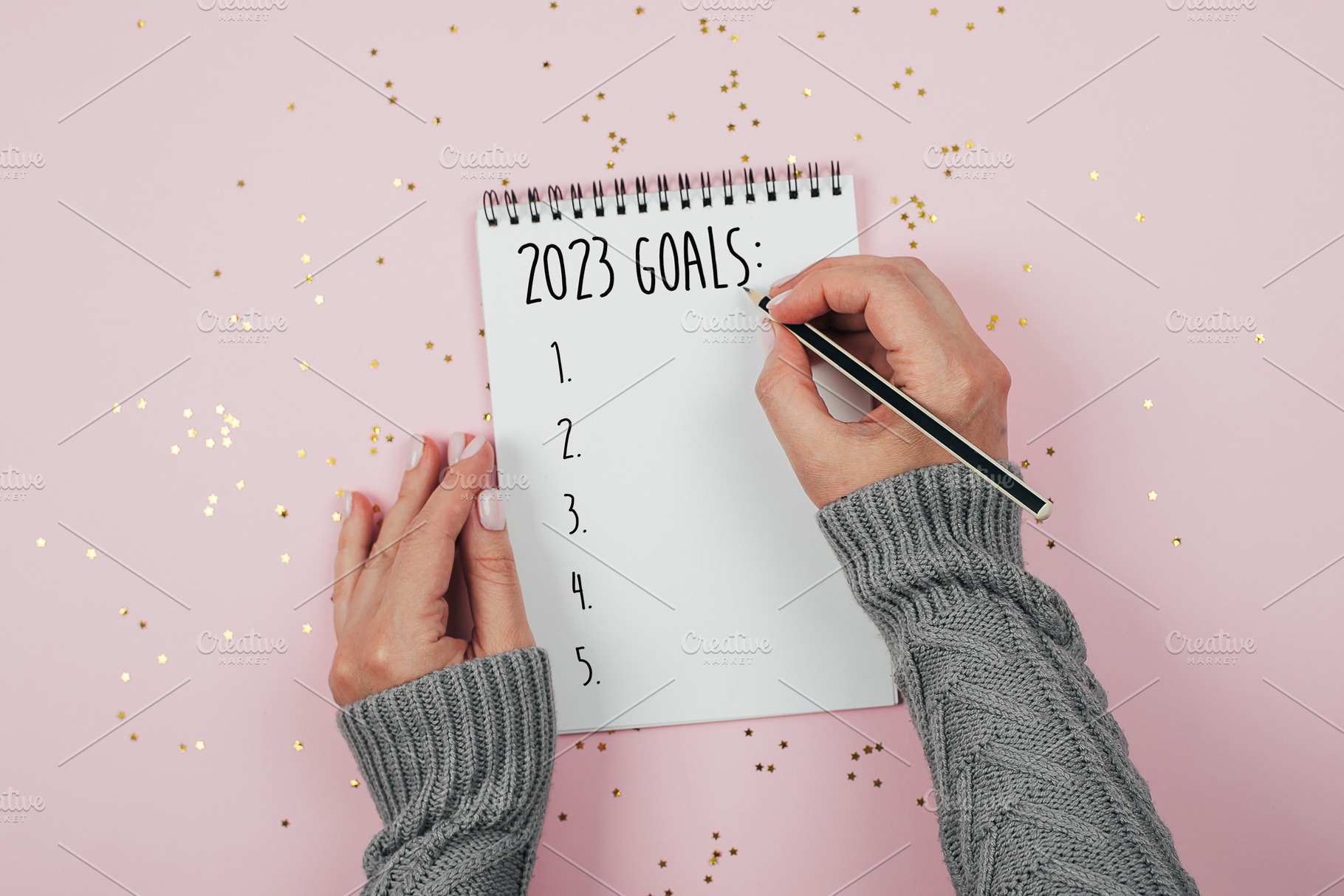 Woman's hand writing 2023 goals in note pad on pink background. Concept of New, a Holiday Photo by Anikona