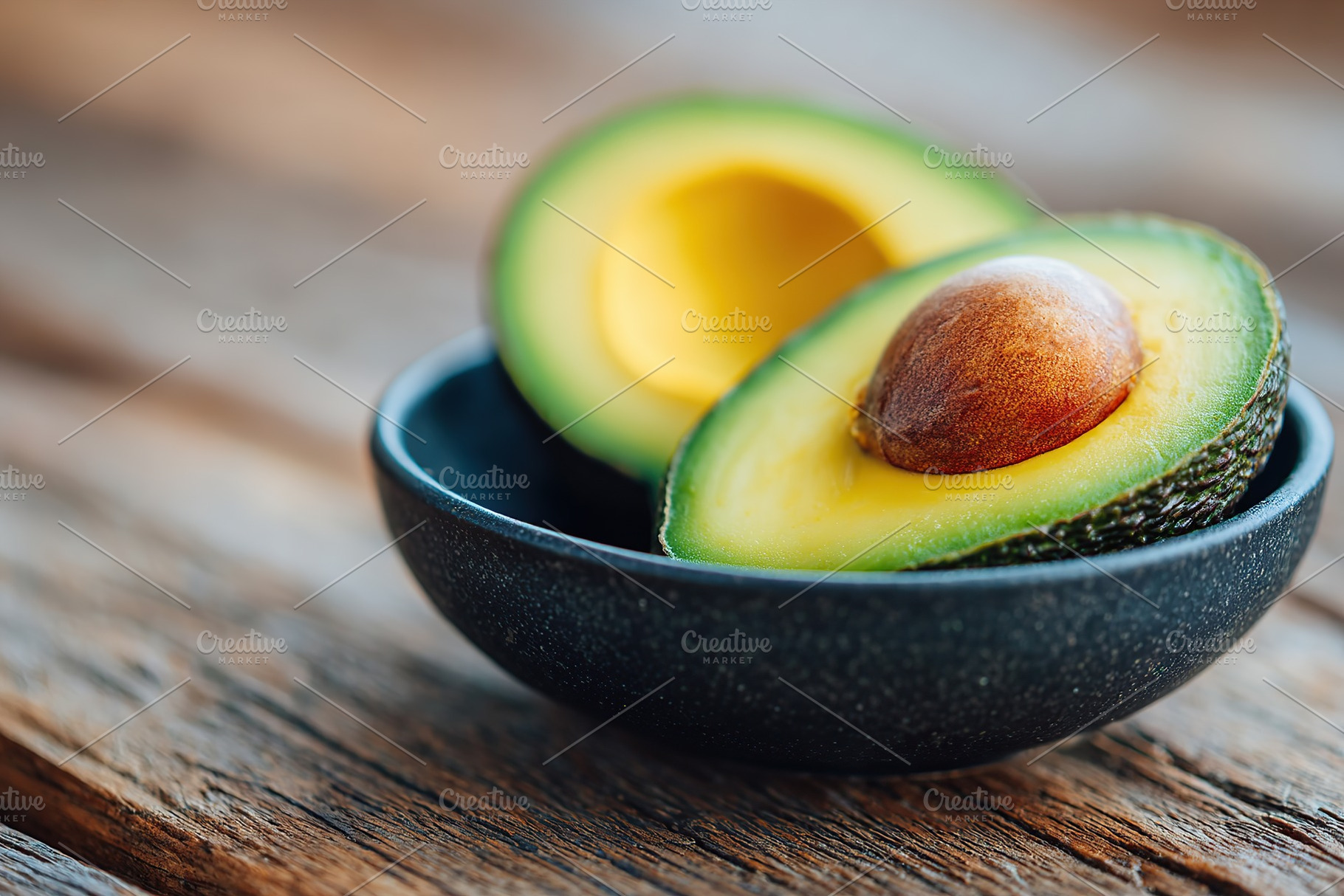 Ripe avocado with bright green pulp displayed in a bowl on wooden table, a Food & Drink Photo by AlyaAnd