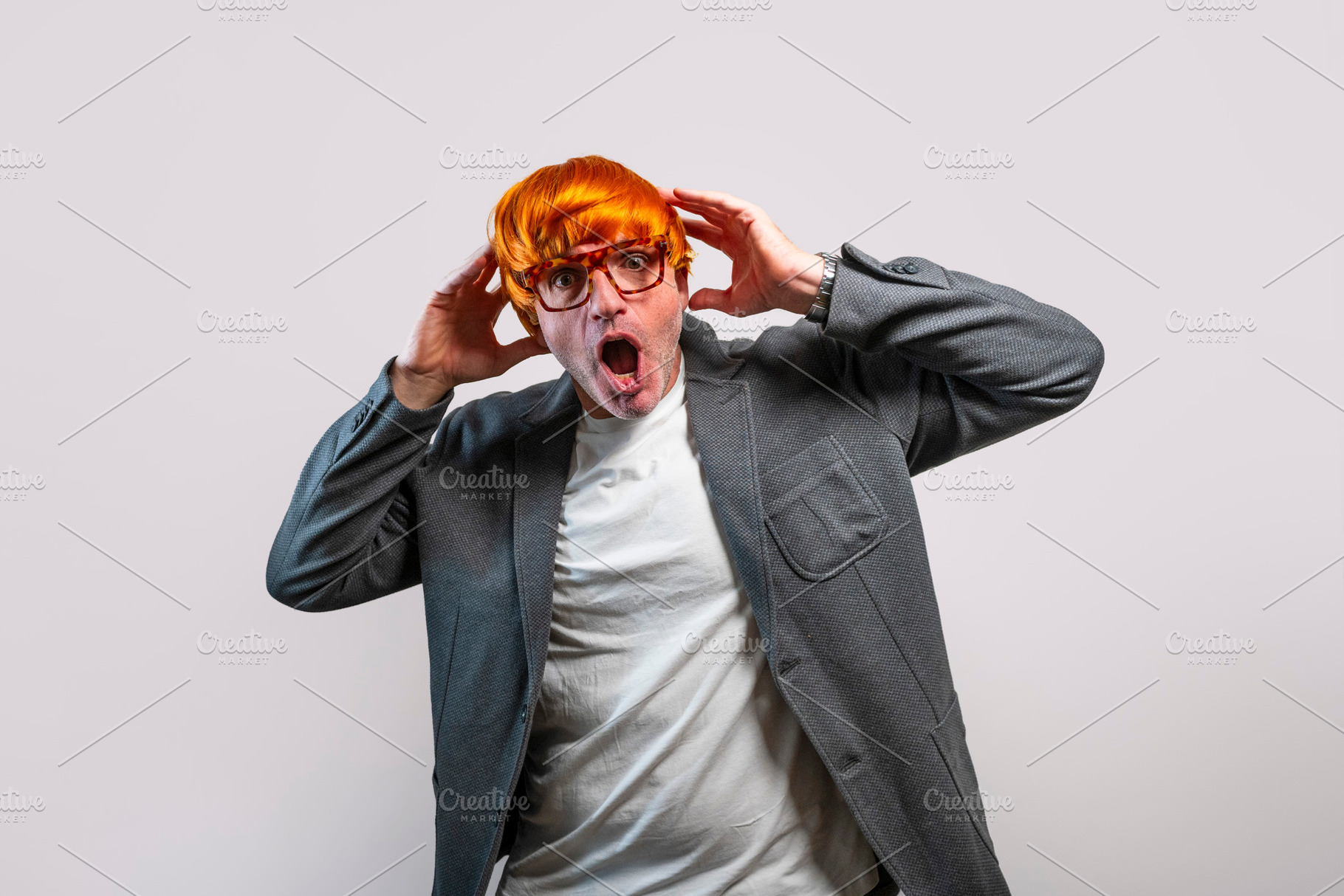 Stressed man in orange wig reacting with shock, a Person Photo by karrastock
