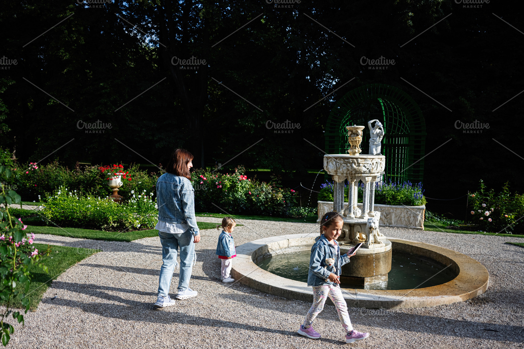 Family enjoying a walk near a fountain in Lancut, Poland garden, a Photo by AS photostudio