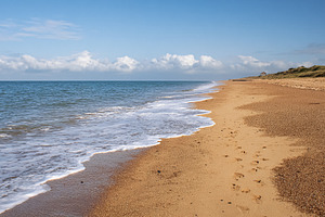 Empty sandy beach with gentle ocean waves rolling to the shore u, a Photo by Studio ANNA