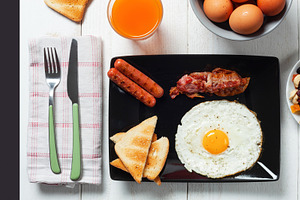 Delicious full english breakfast with fried egg, bacon, sausages and toasts on, a Food & Drink Photo by Antonio Gravante Market