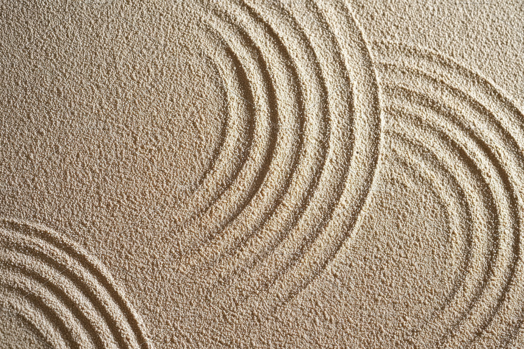 Textured sand with circular wave patterns, a Background Photo by AlyaAnd