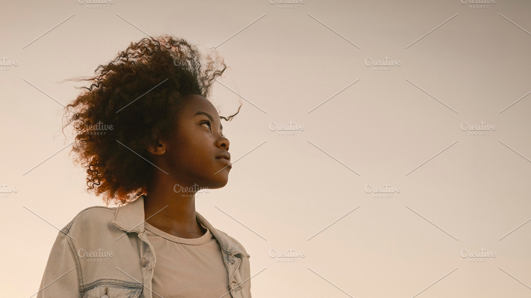 Black woman standing at sunset with city skyline, a Photo by DanFLCreativo