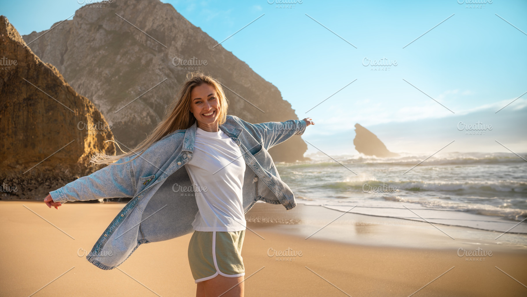 Happy woman standing with arms outstretched on seashore at beach, a Person Photo by andreonegin market