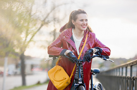 smiling stylish woman in red rain coat outdoors in city, a Person Photo by Alliance Images